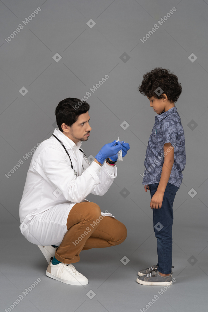 医者は注射器を示しています