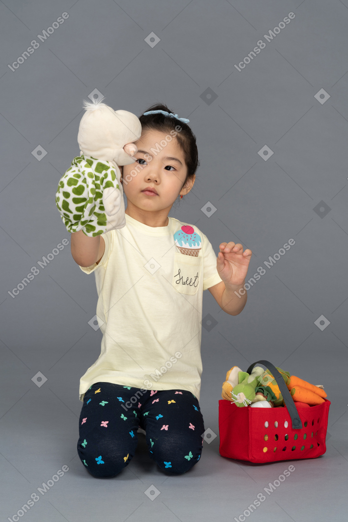 Portrait of a little girl feeding a tortoise puppet