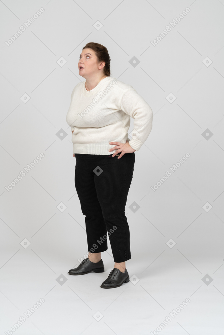Вид сбоку на женщину больших размеров в повседневной одежде, стоящую с руками на бедрах