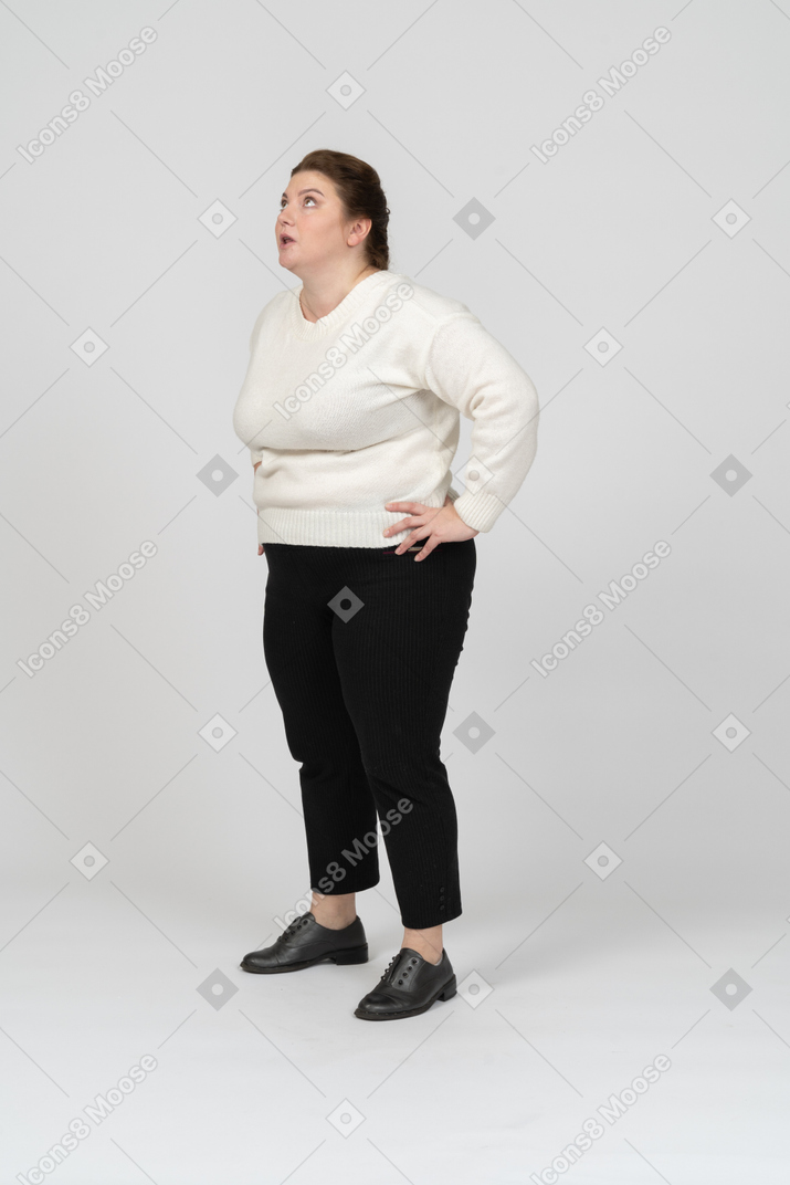 Side view of a plus size woman in casual clothes standing with hands on hips