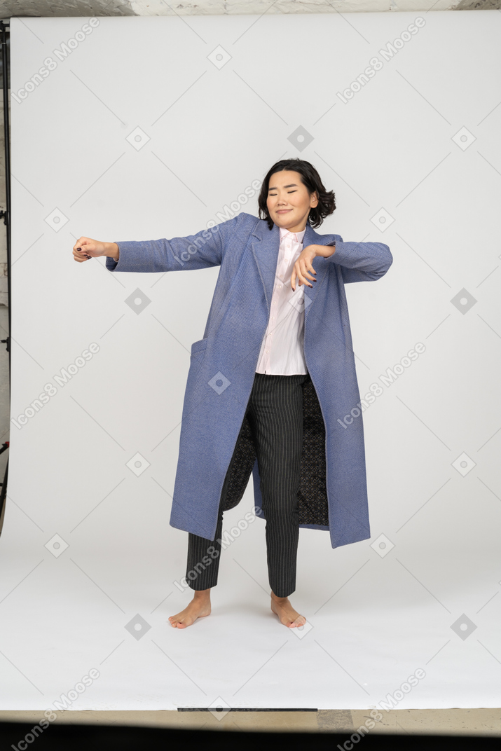 Улыбающаяся женщина в пальто двигает руками
