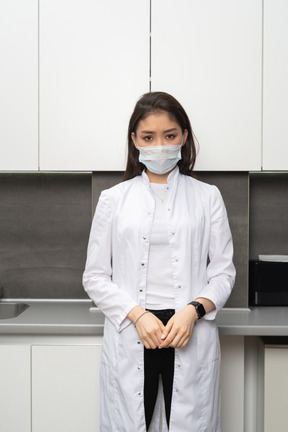 Vue de face d'une femme médecin douteuse mettant les mains ensemble et regardant la caméra