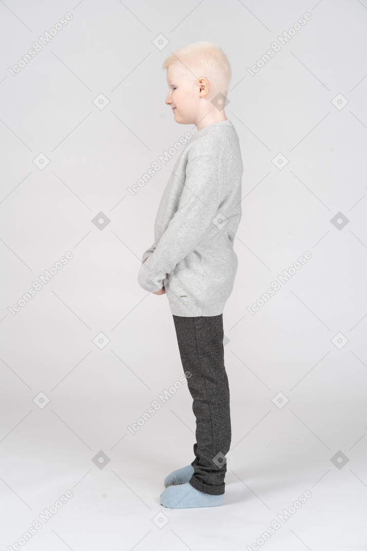 Vista lateral de um menino loiro tímido