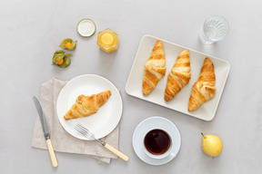 Some coffee, croissants, honey and a pear