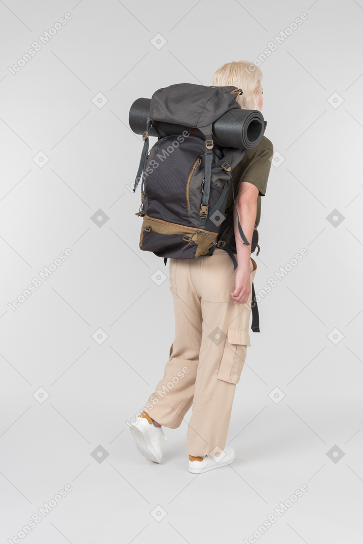 Female tourist with huge backpack standing back to camera