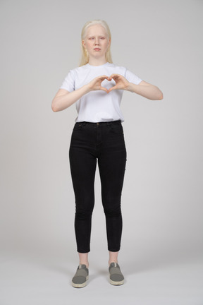 Front view of a young girl standing and showing heart