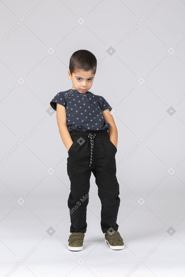 Front view of a cute boy posing with hands in pockets and bending back