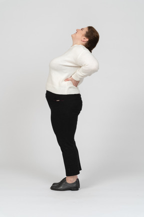 Mujer de talla grande en ropa casual que sufre de dolor en la espalda baja