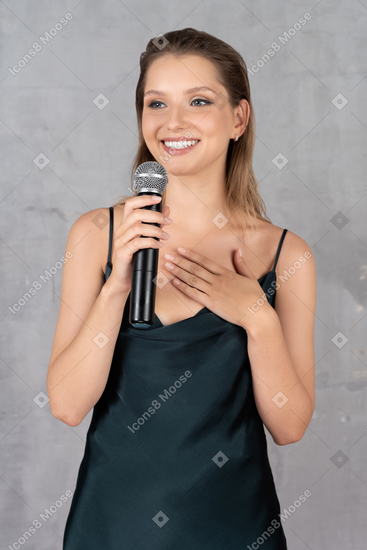 Front view of a smiling young woman in night gown holding a microphone