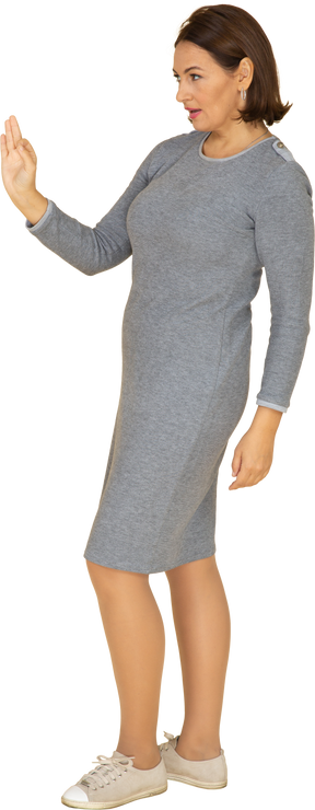Vista laterale di una donna in abito grigio che mostra segno ok