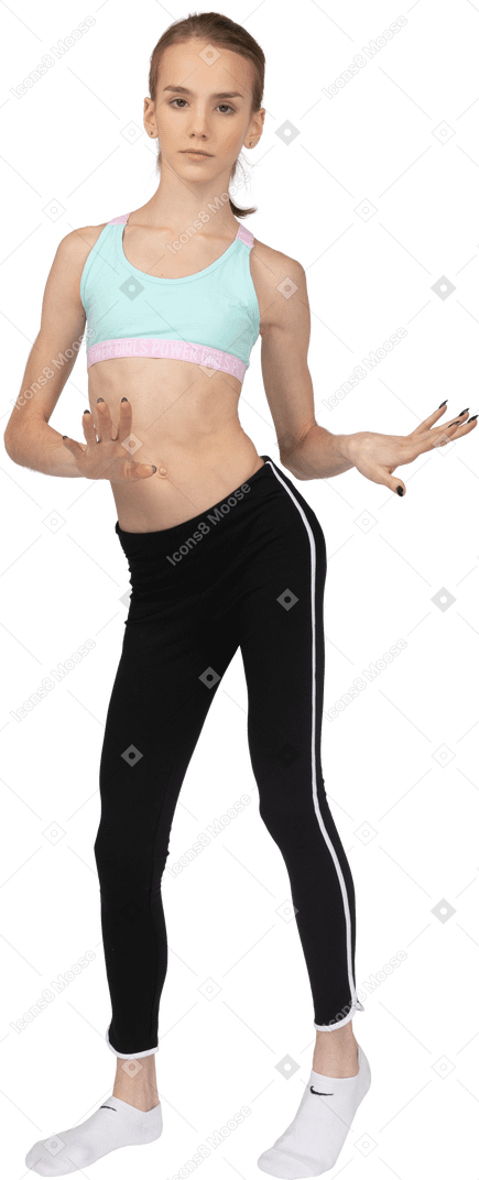 Vista frontal de una jovencita en ropa deportiva bailando mientras gesticula