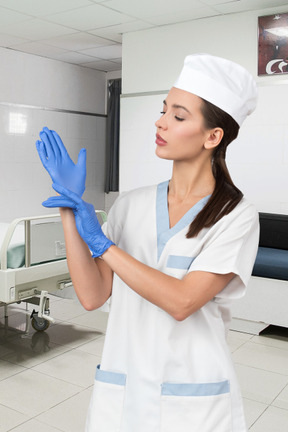 Woman dressed as a nurse and putting on medical gloves
