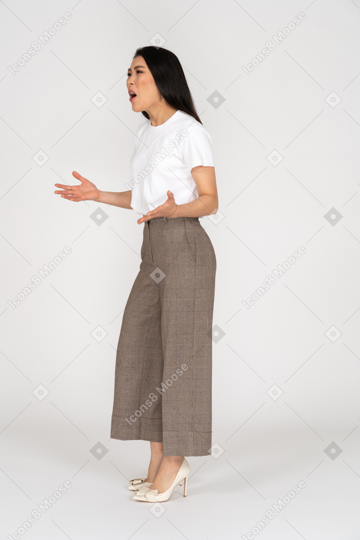 Three-quarter view of a shouting gesticulating young lady in breeches and t-shirt