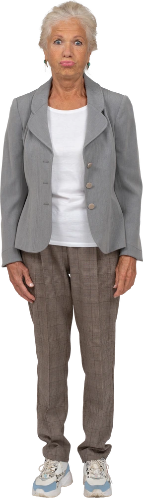 Vista frontal de una anciana en traje mirando a la cámara y haciendo muecas