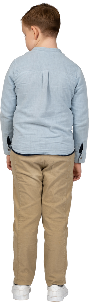 Vista trasera de un niño con ropa informal mirando hacia abajo