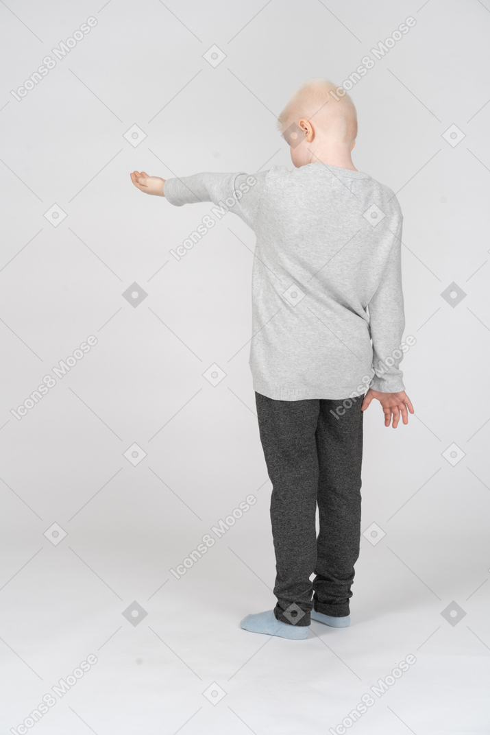 Back view of a boy holding out his hand