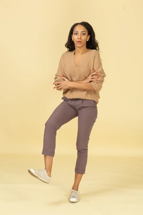 Front view of a surprised dark-skinned young female crossing hands