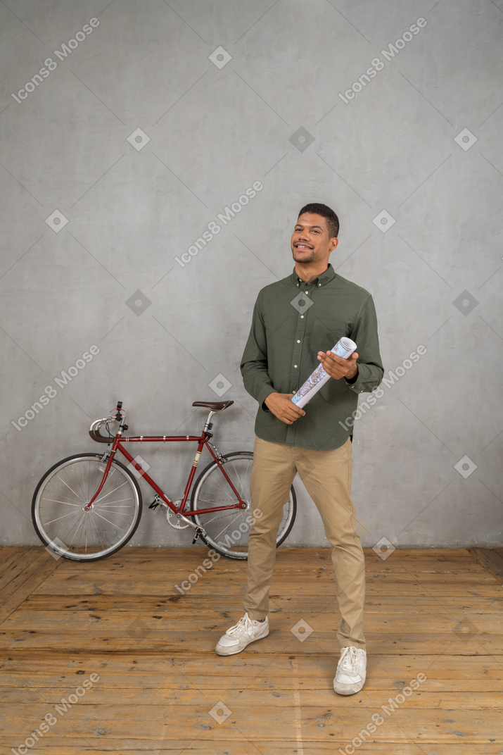 Vue de trois quarts d'un homme tenant une carte roulée avec un sourire