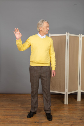 Vista frontal de un anciano levantando la mano