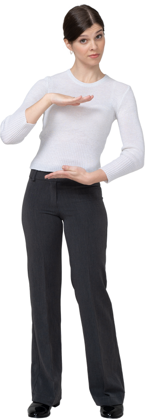 Vista frontal de uma jovem com roupa de escritório, mostrando o tamanho de algo