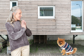 A woman standing in front of a house next to a dog