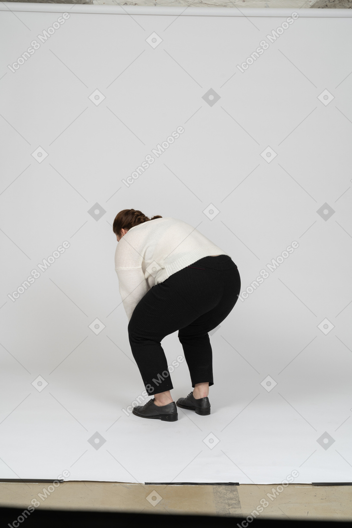 Vista posteriore di una donna grassoccia in abiti casual che si china