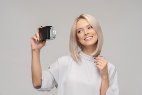 Mujer joven sonriente tomando un selfie con una vieja cámara