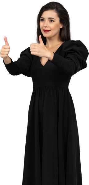 Vista de três quartos de uma jovem sorridente em um vestido preto mostrando os polegares para cima