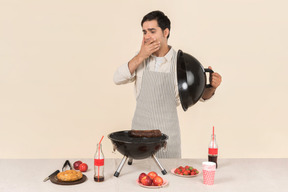 Ofegante jovem homem caucasiano preparando um churrasco