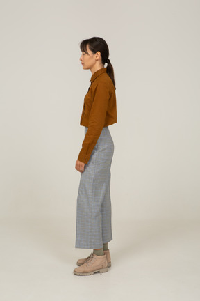 Side view of a young asian female in breeches and blouse narrowing eyes