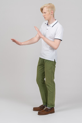 Side view of a young man showing stop gesture