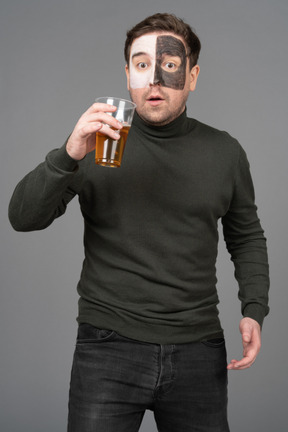 Front view of a surprised male football fan holding a beer