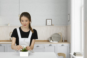 A woman standing in a kitchen holding a plant