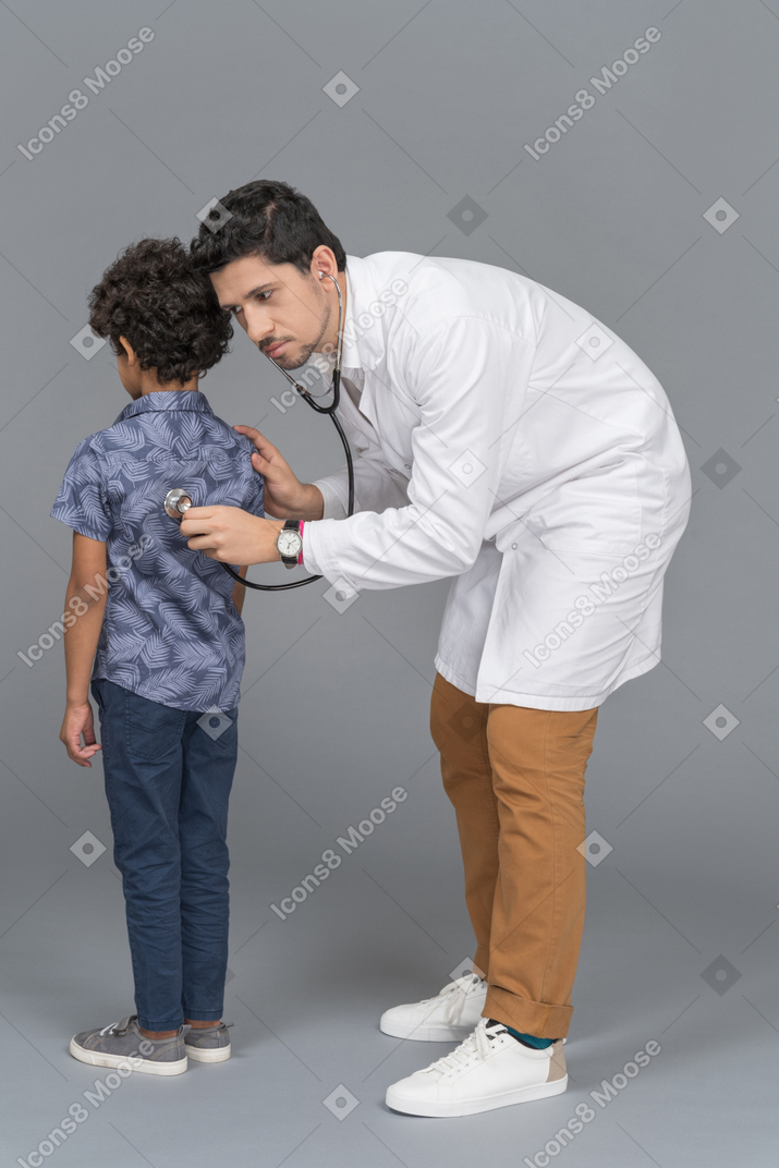 Médico con estetoscopio examinando a un niño