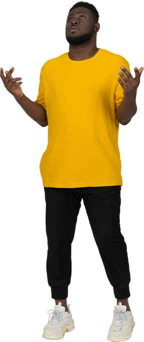 Vista frontal de un joven de piel oscura con camiseta amarilla parado