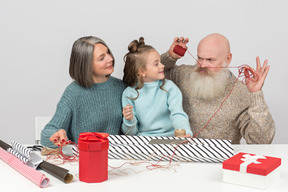 Nonno scherzare intorno a confezionare regali con moglie e nipote