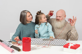 Vovô brincando envolvendo presentes com esposa e neta