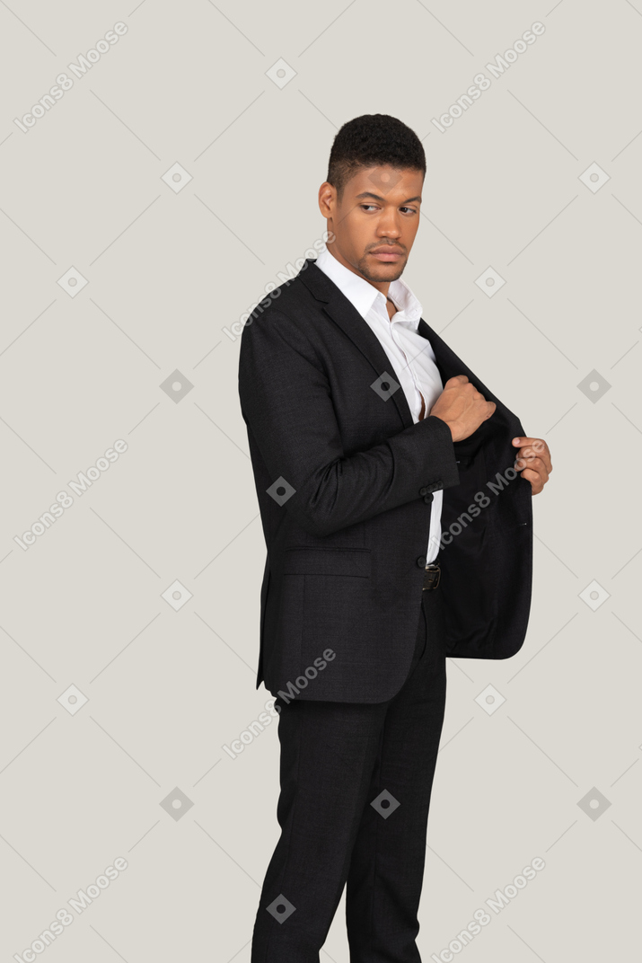 Vista laterale di un giovane in abito nero che mette qualcosa in tasca