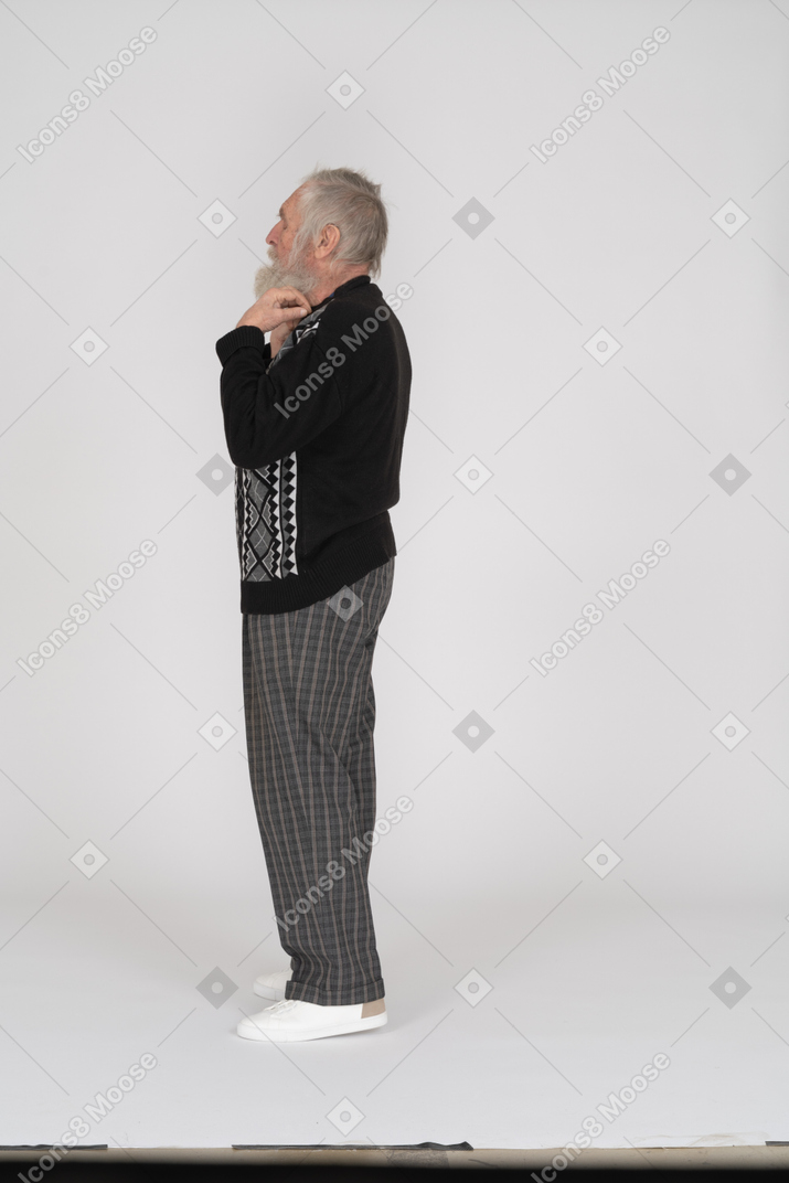 Vista laterale di un uomo anziano che si regola il colletto
