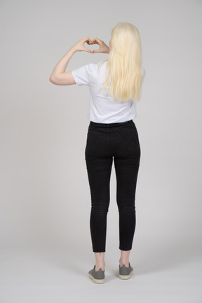 Rear view of a young girl with heart hand sign