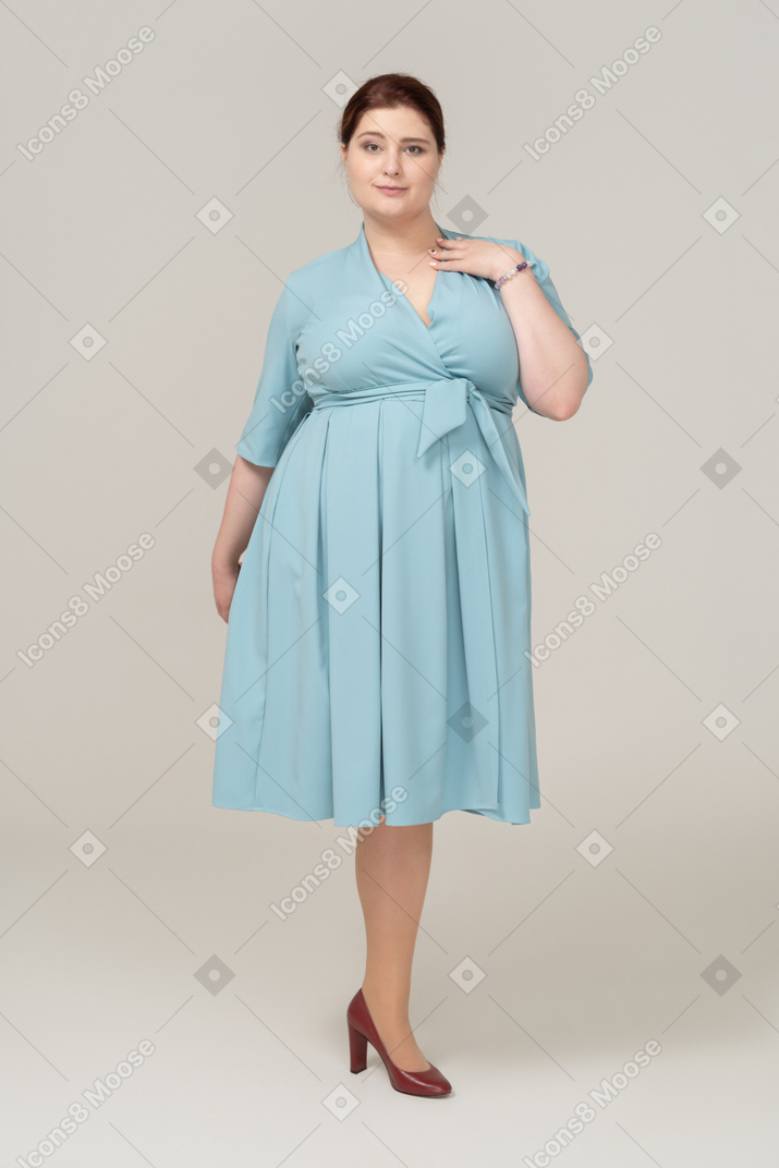 Front view of a woman in blue dress posing with hand on shoulder