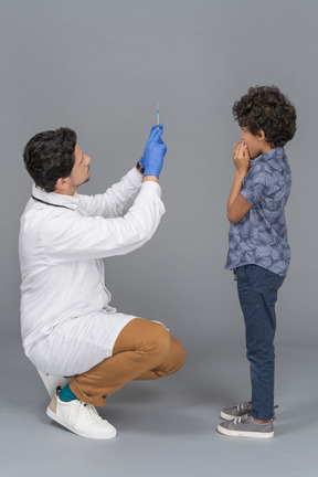 Médico mostrando seringa para um menino