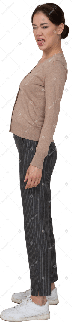Вид сбоку гримасничающей молодой леди в бежевом пуловере