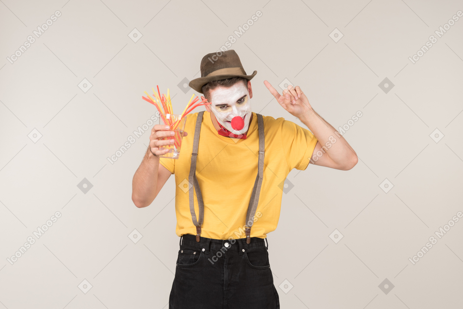 Male clown holding glass with plastic straws in it