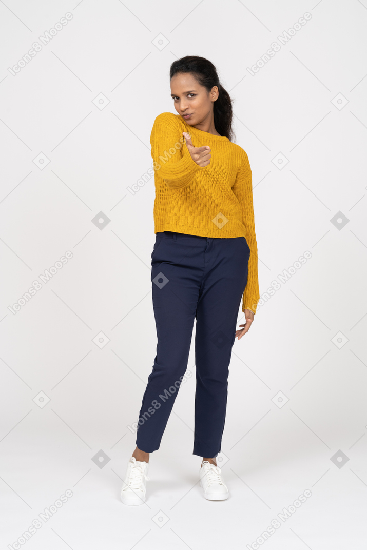 Front view of a girl in casual clothes pointing with a finger