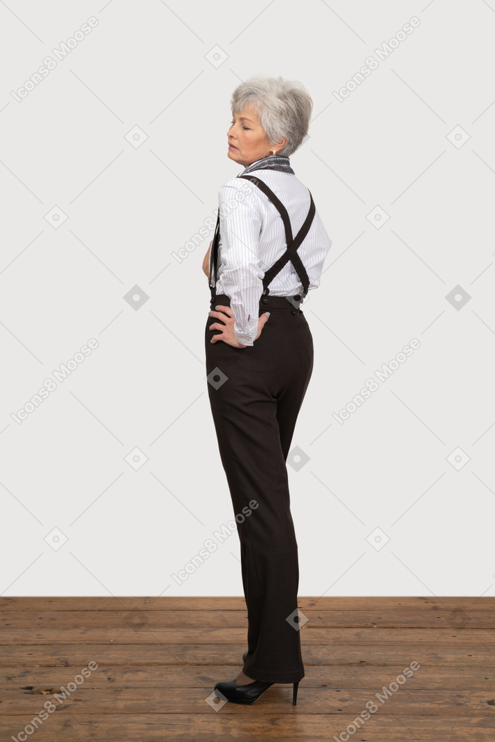 Vista posteriore di tre quarti di una vecchia signora che mette le mani sui fianchi