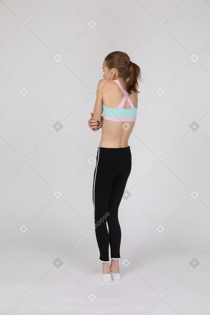 Vista traseira de três quartos de uma adolescente trêmula em roupas esportivas
