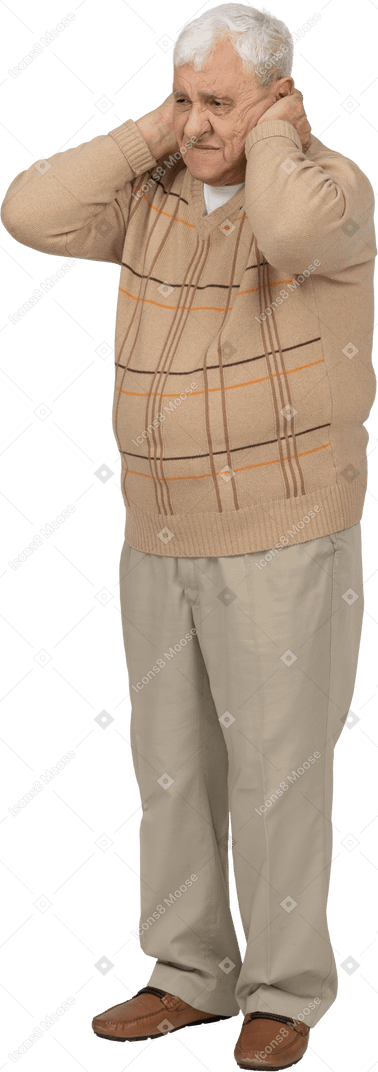 Front view of a sad old man in casual clothes covering ears with hands
