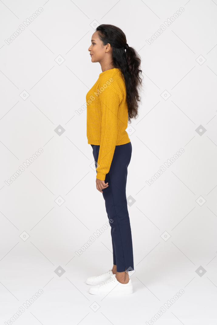 Giovane donna felice in abiti casual in piedi di profilo