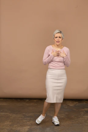 Front view of an impressed woman in casual clothes standing with hands on chest